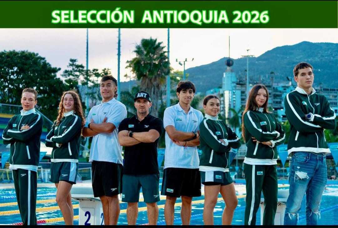Fotografía grupal de ocho atletas y un entrenador de la Selección Antioquia de natación 2026, de pie frente a una piscina olímpica al aire libre.