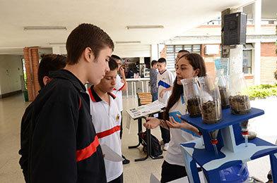 Estudiante del bachillerato femenino presentado su trabajo de investigación sobre suelos a dos estudiantes del bachillerato masculino durante una feria de las ciencias