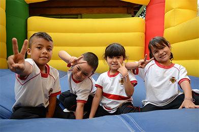 Dos niños y dos niñas posando para la foto mientras juegan en un castillo inflable