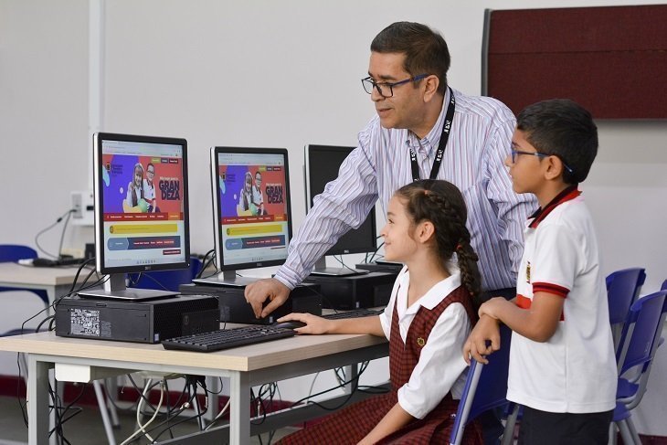 profesor explicándole a estudiantes como manejar computador 