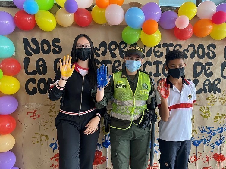 Policia y estudiantes con bandera de Colombia en la mano
