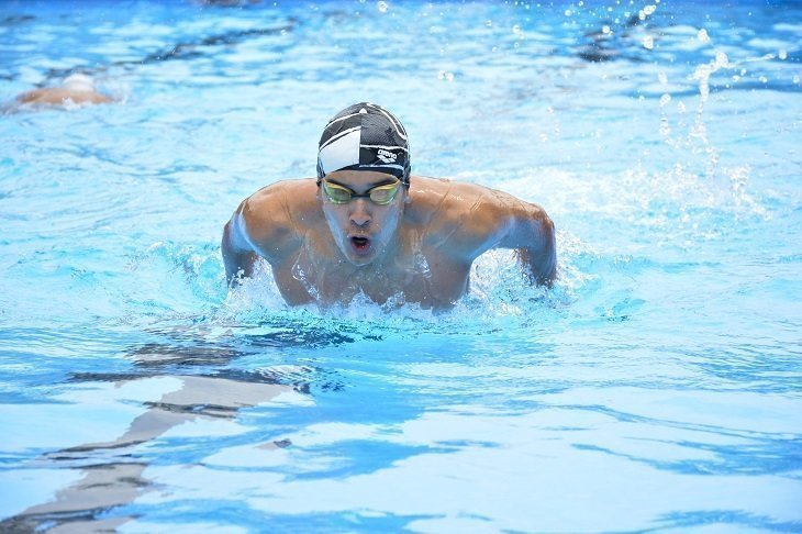 Un joven nadando en la piscina a lo profesional
