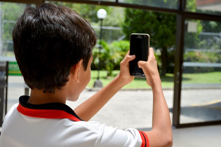 Este es un estudiante de espaldas sosteniendo un celular