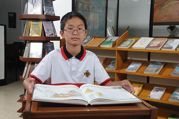 Estudiante del colegio con rasgos asiáticos leyendo un libro en la biblioteca