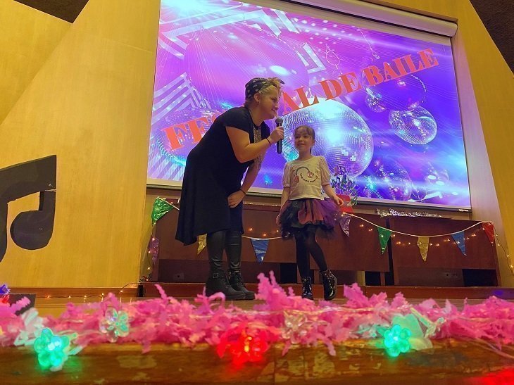 Profesora hablando con niña por micrófono 