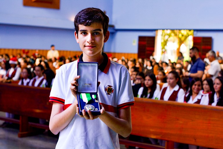 Estudiante del Colegio sosteniendo la Medalla al Mérito educativo.