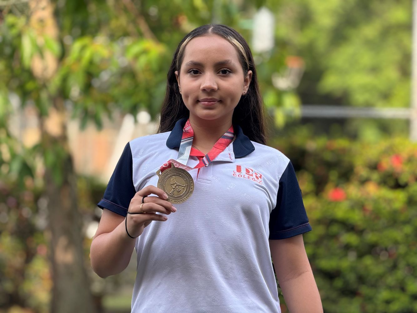 Retrato de una joven deportista sosteniendo una medalla ganada en hockey.