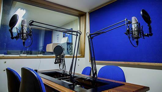 Sala de grabación de audio con cuatro puestos y micrófonos