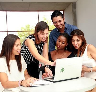 profesor le señala algo a una estudiante en el computador. 