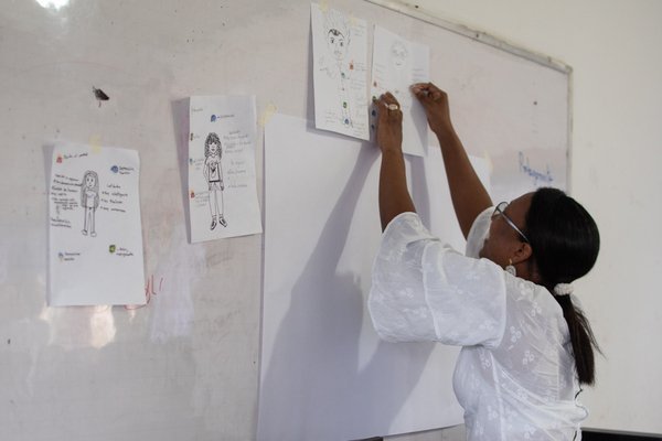 Docente pegando hojas en tablero de clases