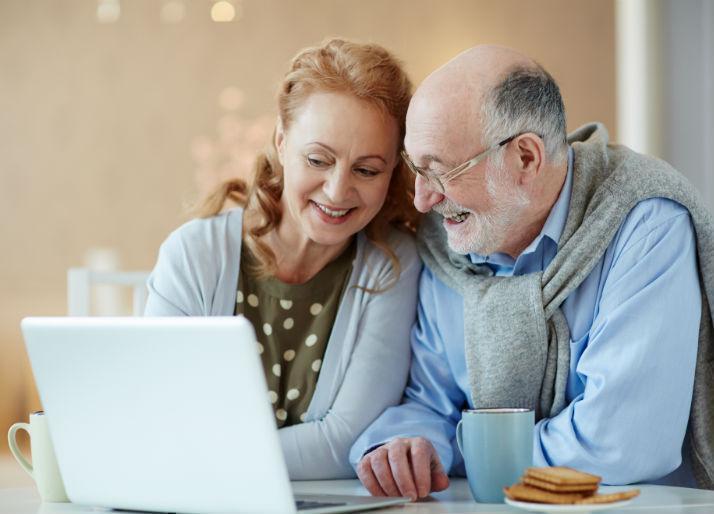 Personas adultas mayores sonríen frente a un computador