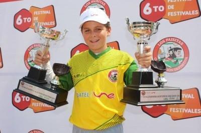 Julián Sánchez con el uniforme de su equipo, levanta sonriente un trofeo en cada mano.