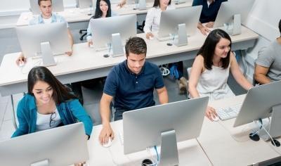 Estudiantes en clase al frente de unos computadores