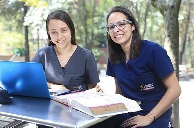 Estudiantes trabajando con un libro frente a un computador