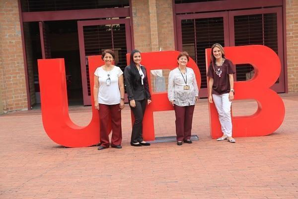 Empleadas posando frente a las letras UPB