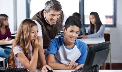 profesor con dos estudiantes mirando un computador
