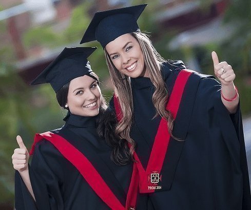 Dos estudiantes mujeres con vestuario de graduación