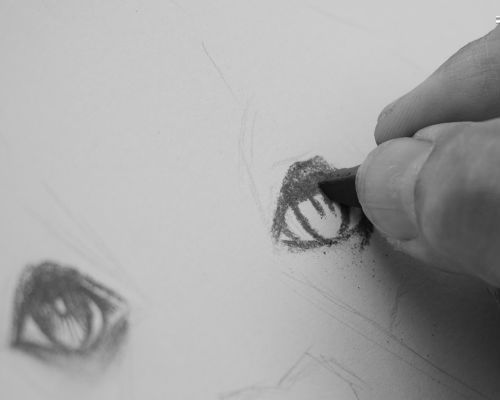 manos dibujando un ojo con carboncillo