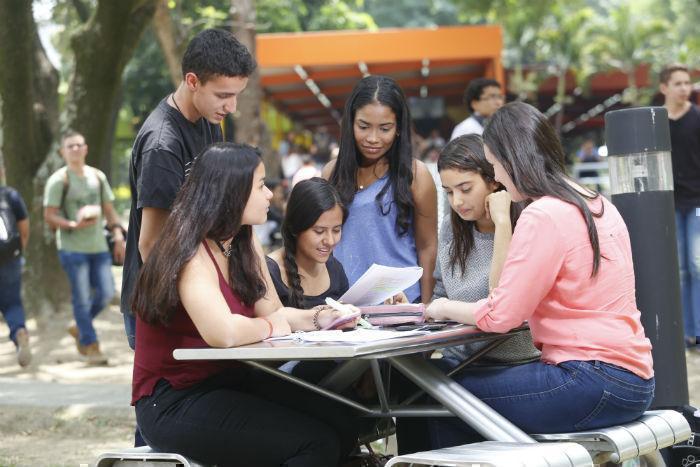 Grupo de estudiantes sentado en una mesa en los jardines del campus mirando unos documentos