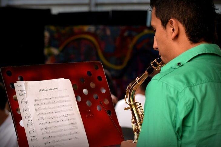 persona tocando el saxofón y leyendo la partitura
