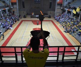 Deprtista prendiendo llama olimpica. Se observa un plano genral del polideportivo
