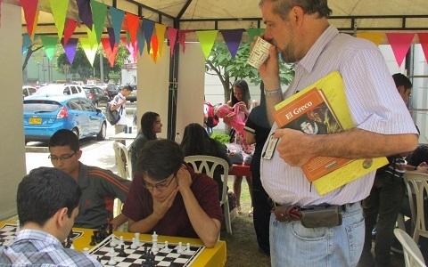Estudiantes jugando ajedrez y un proesor viendo el juego