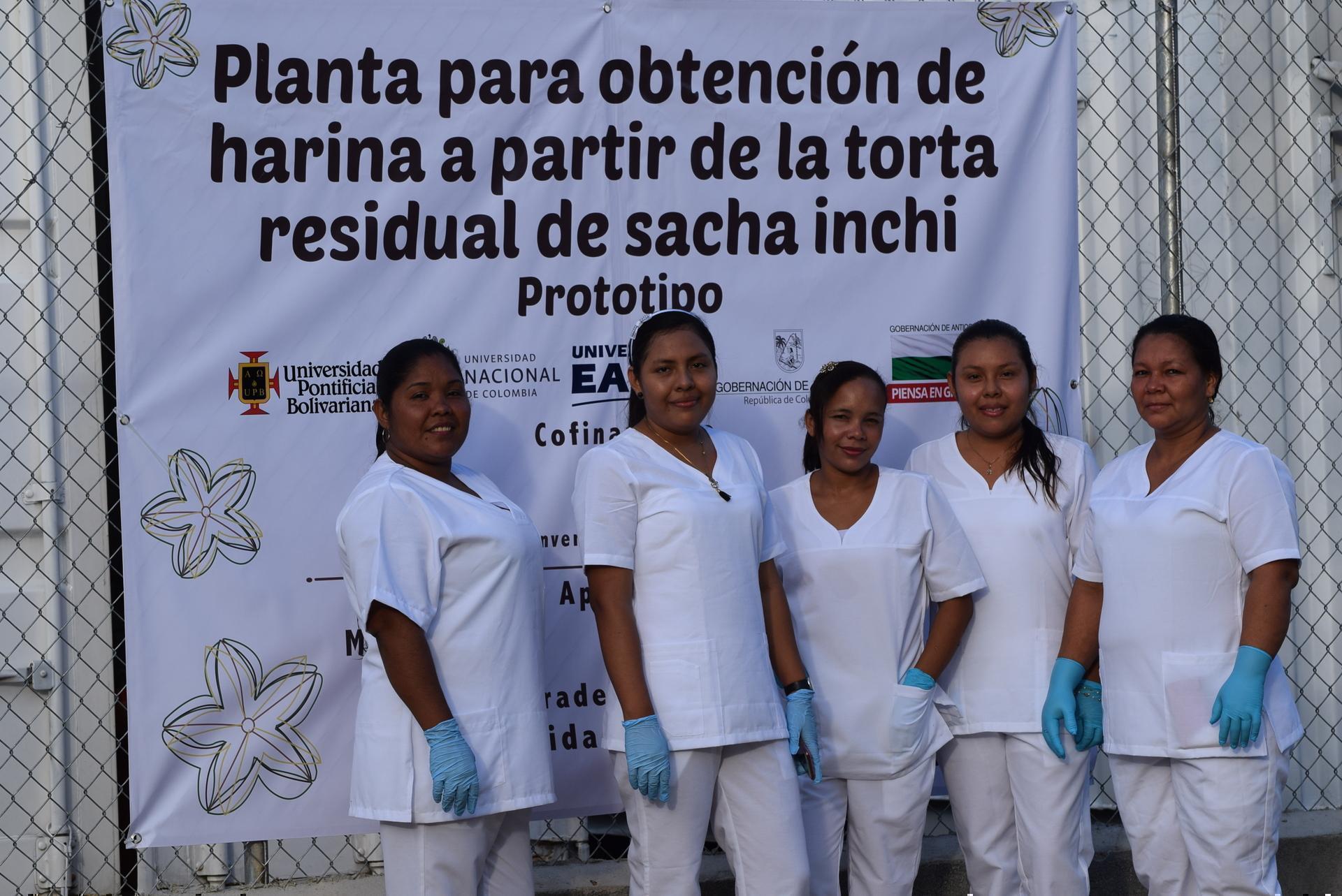 mujeres con uniforme y guantes posando delante de poster de la planta