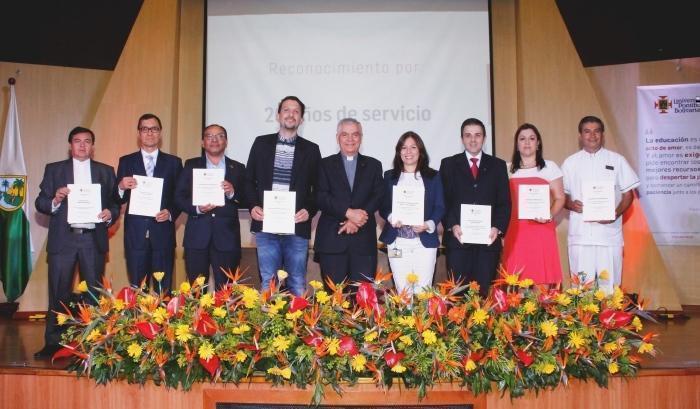 Directores de unidades académicas junto con el Rector en el escenario. Los directores muestran el diploma.