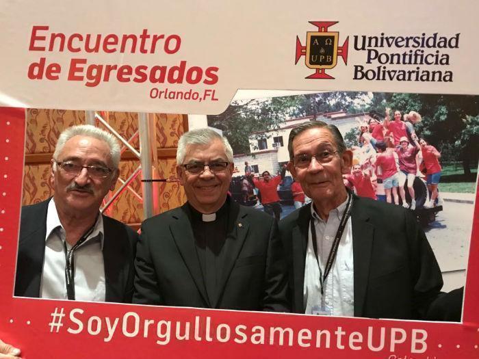 Rector y dos egresados detrás de un marco que dice #SoyOrgullosamenteUPB