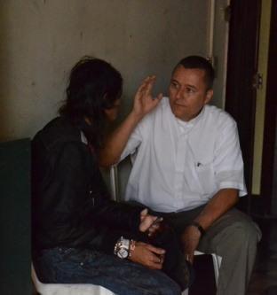 Padre Julián sentado dándole la bendición a una persona.