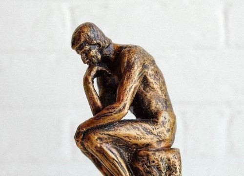 Estatua de una persona sentada con la mano en la mandíbula pensando