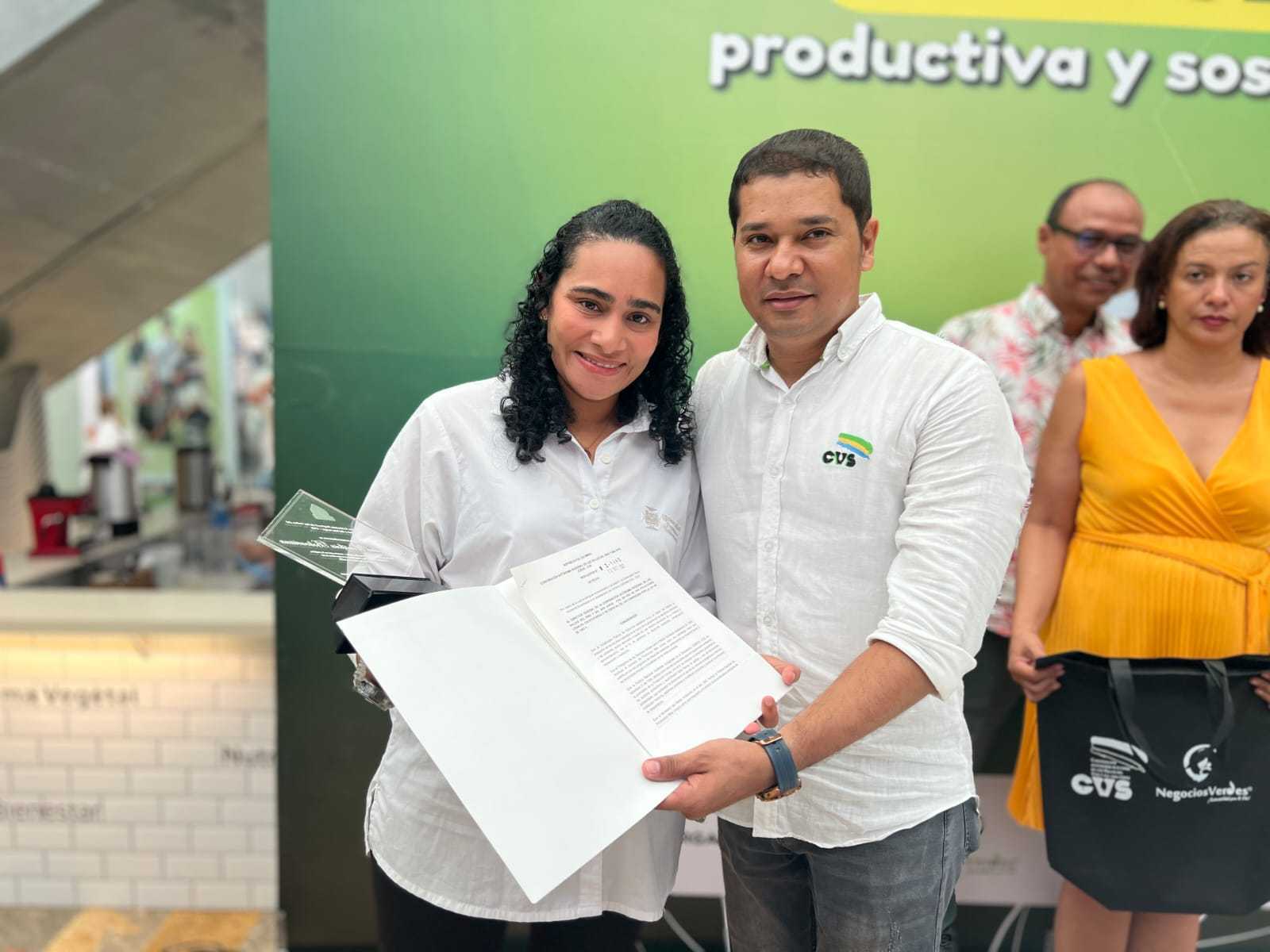Vanessa De la Torre Mendoza, coordinadora UPB Sostenible, recibiendo el reconocimiento por Albeiro Arrieta, Subdirector de Sostenibilidad CVS