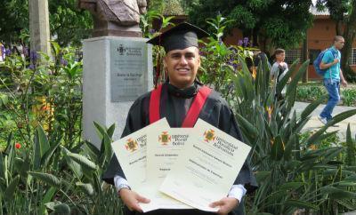 Daniel Amaya con toga y birrete sostiene los tres diplomas. Daniel hizo su inscripción a la Universidad a 3 programas.