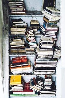 En un hueco que hay en una pared, se encuentran unos entrepaños y en medio de ellos se hallan libros y cuadernos amarrados y apilados.