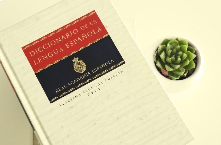 Sobre una superficie se encuentra un libro abierto, de pasta dura anaranjada