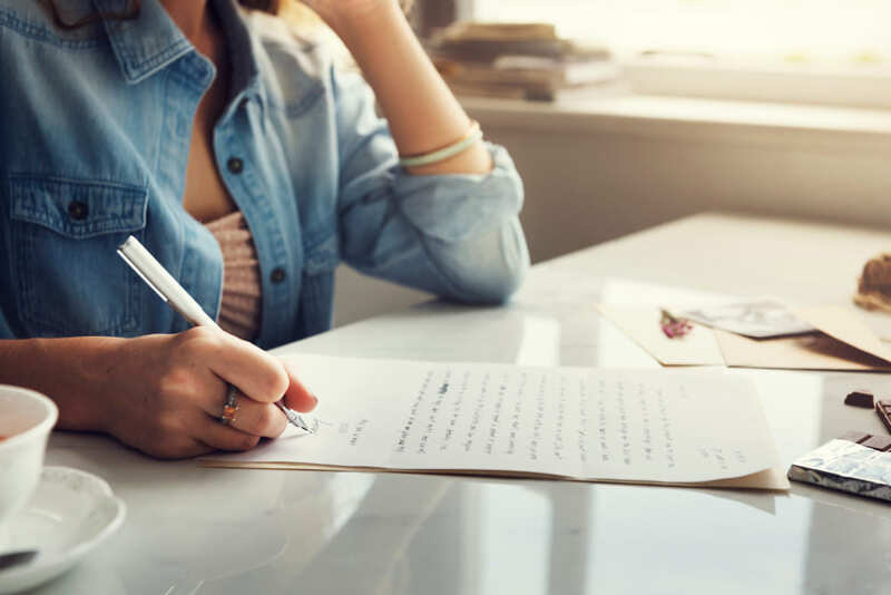 Mujer escribiendo con lapicero sobre hoja de papel