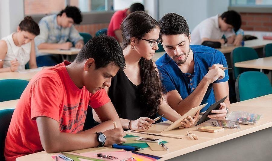 Tres estudiantes dialogando en escritorio