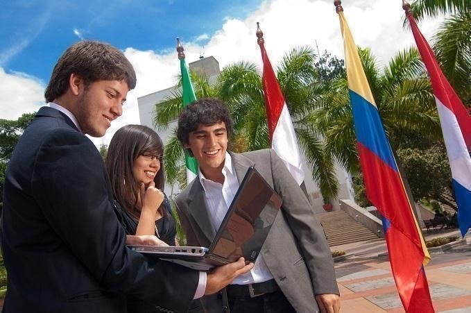 Estudiantes mirando computador con banderas de paises en el fondo