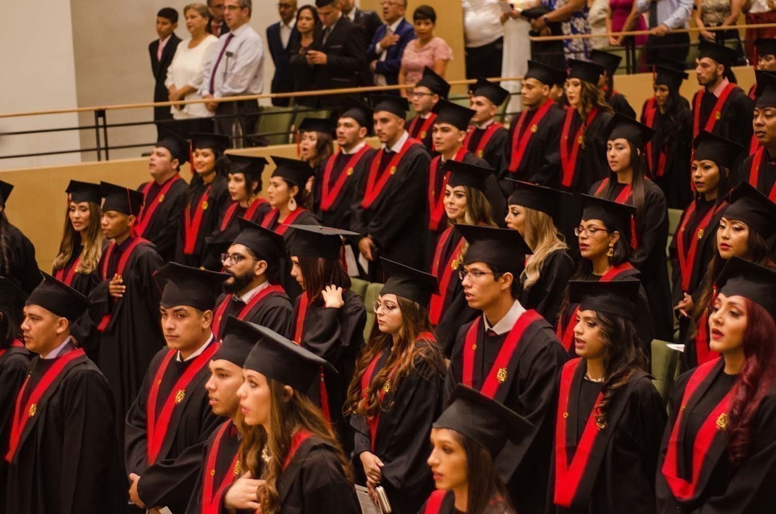 Estudiantes con toga de graduación en auditorio