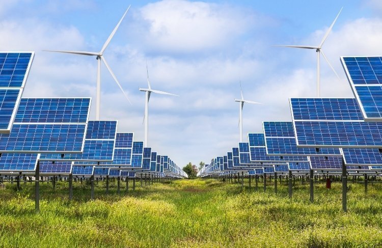 Paneles solares y turbinas eólicas que generan energía en medio de un terreno con hierba