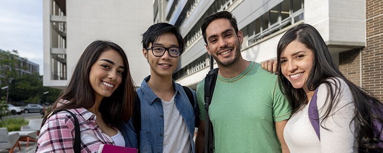 Cuatro estudiantes sonriendo y mirando a la cámara