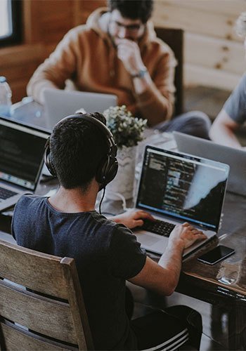 Hombre sentado trabajando en programación frente a computador acompañado