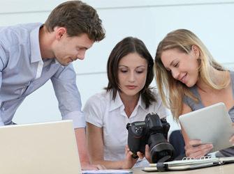 Tres personas mirando fotografías en una cámara 