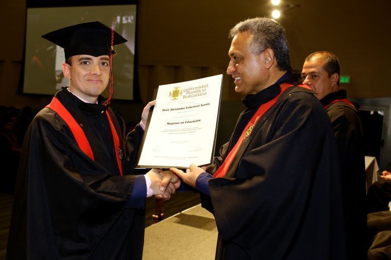 Jhon Alexander recbiendo el diploma de magister en educación con el rector de la UPB
