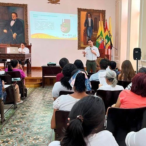 Foto de auditorio con personas recibiendo conferencia